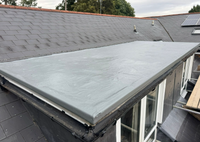 A professionally repaired GRP flat roof extension featuring a seamless Concrete Grey waterproof coating and new high-performance guttering.